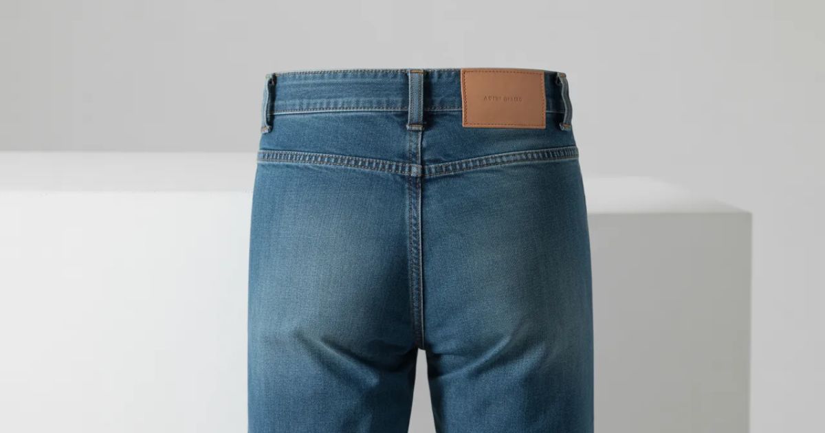 Model wearing mid rise jeans styled with a white shirt in an outdoor setting.