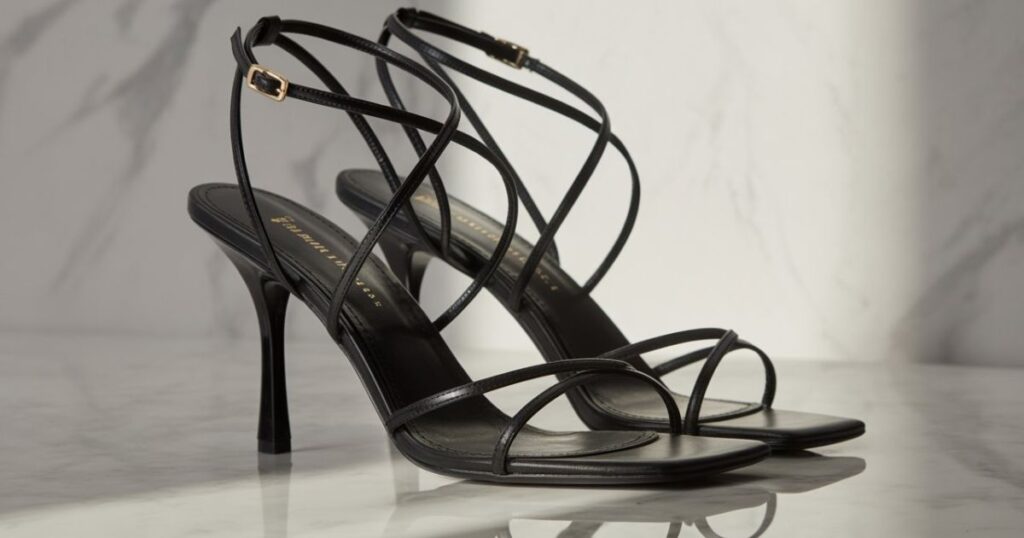 Black strappy heels with thin ankle straps displayed on a white background.